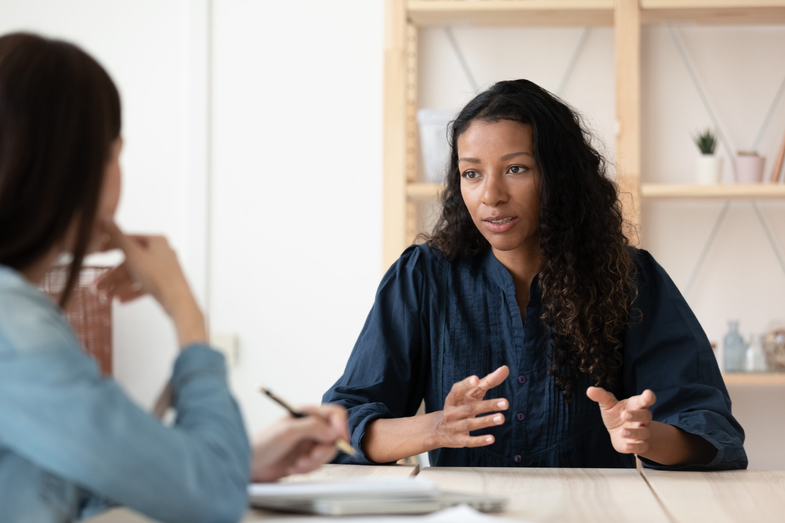 Woman talking with hands and woman makes notes
