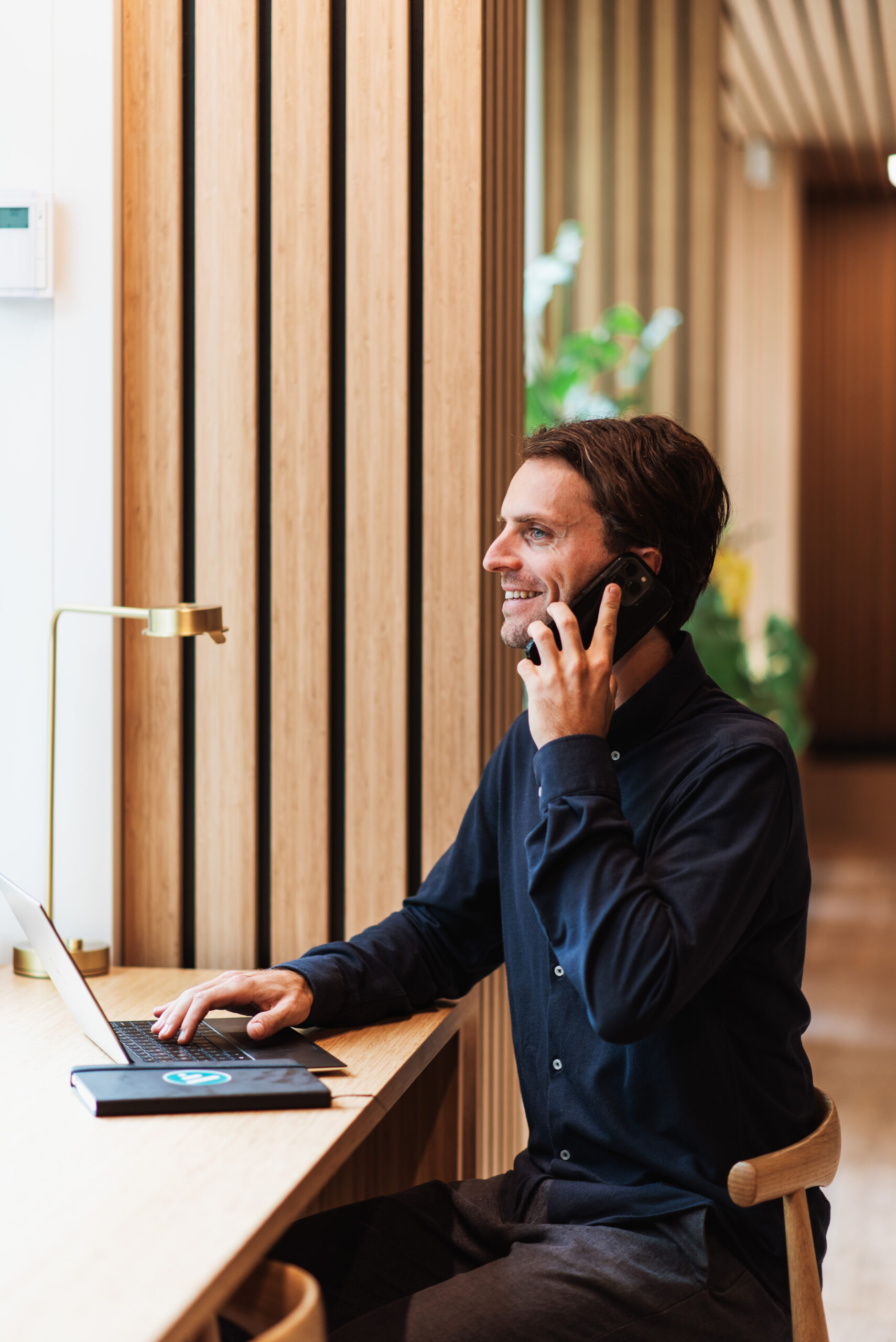 Man i kontorsmiljö som pratar i telefon framför sin dator