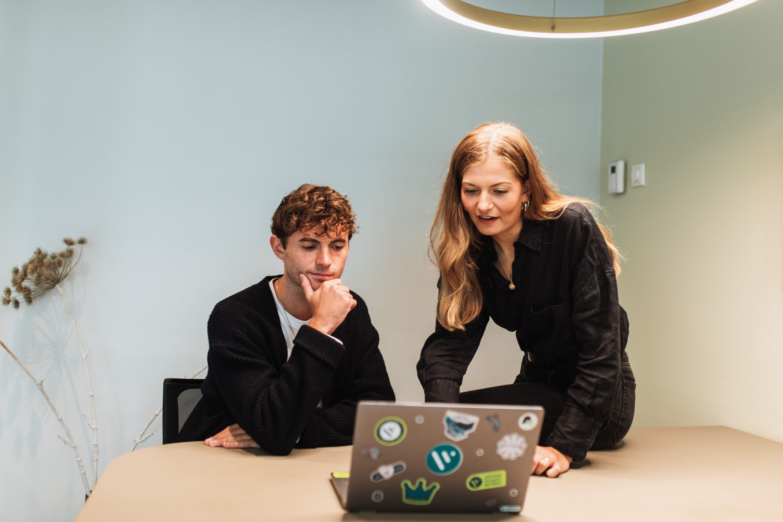 Two colleagues working at a laptop in an office