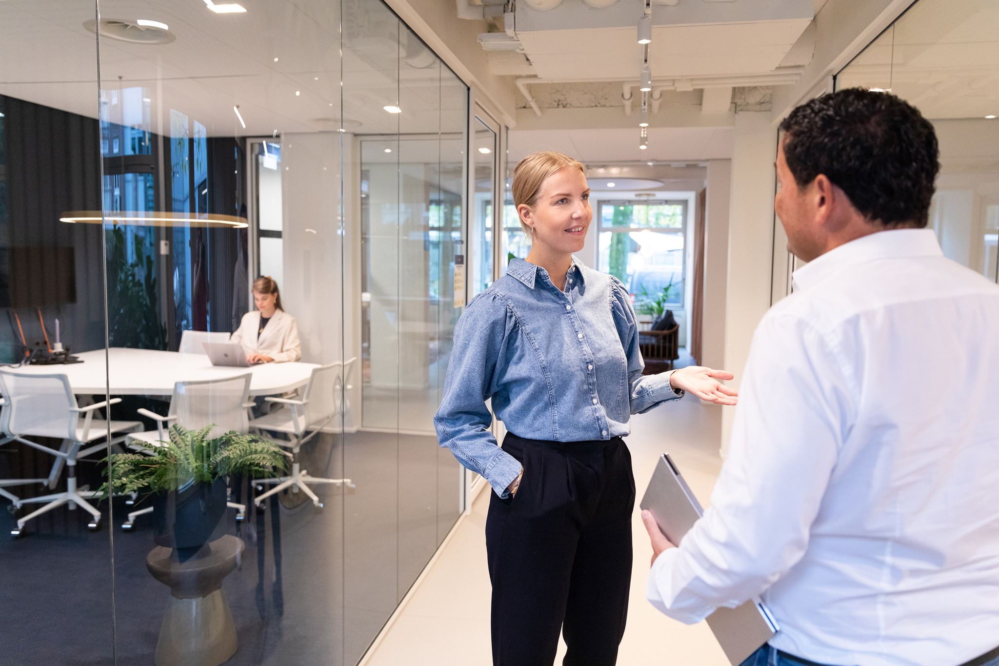 Two colleagues in conversation in a modern office environment, illustrating professional and structured recruitment or compliance processes.