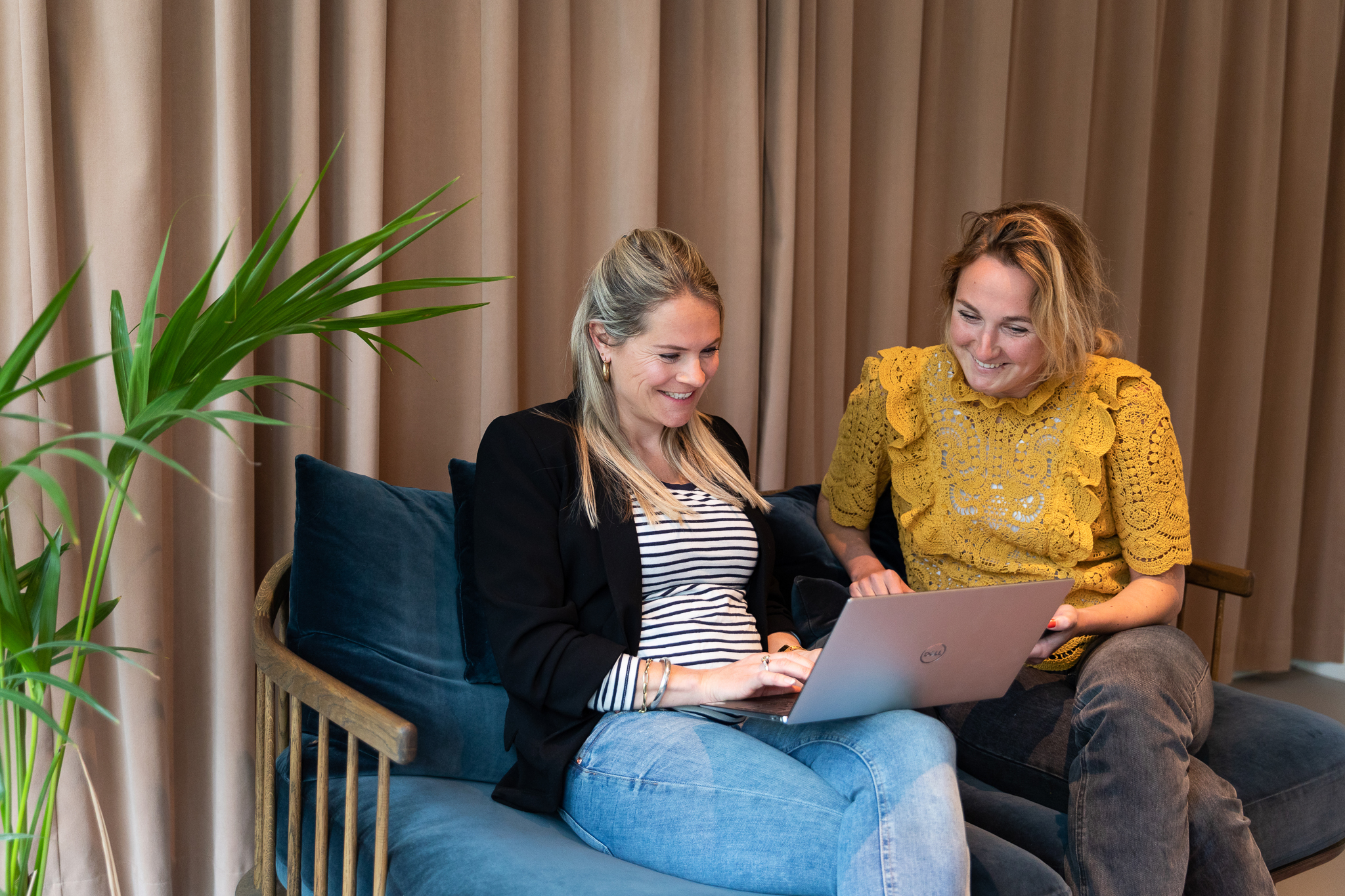 Två kvinnor som sitter i en soffa och kollar på en dator
