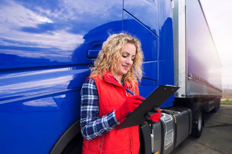 Portrait of truck driver doing paperwork by truck vehicle. Transportation service