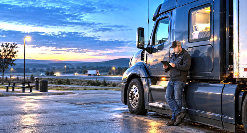 truck driver during blue-hour ELD review at rest area