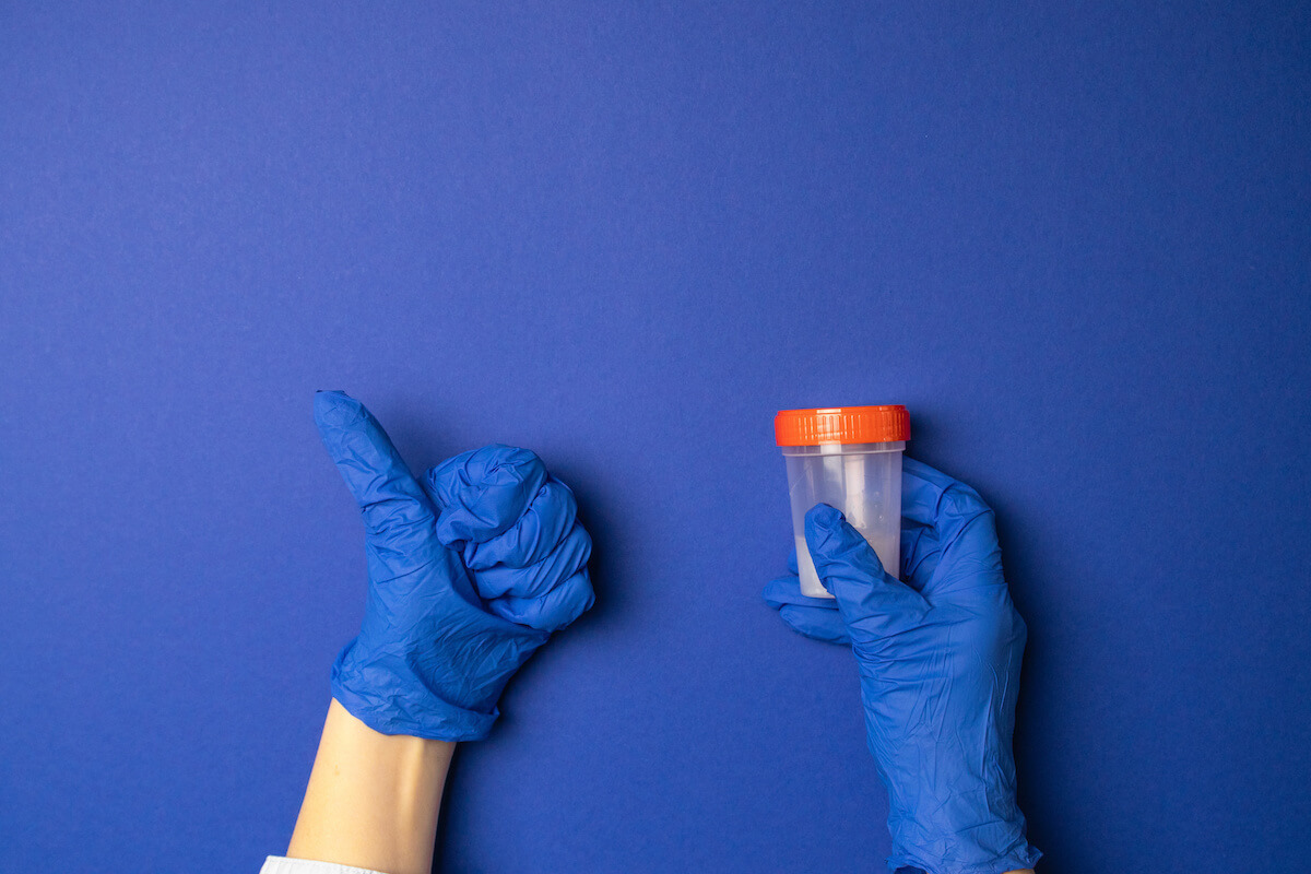 Gloved hands holding a drug test sample and giving a thumbs up