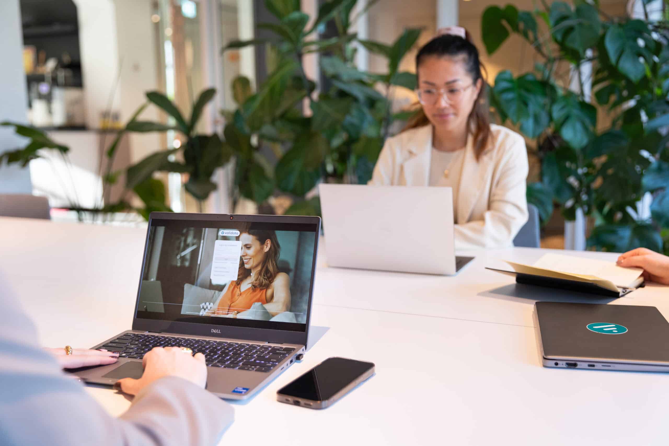 coworkers sitting at a conference table working on laptops, one worker is logging into the DISA screening platform