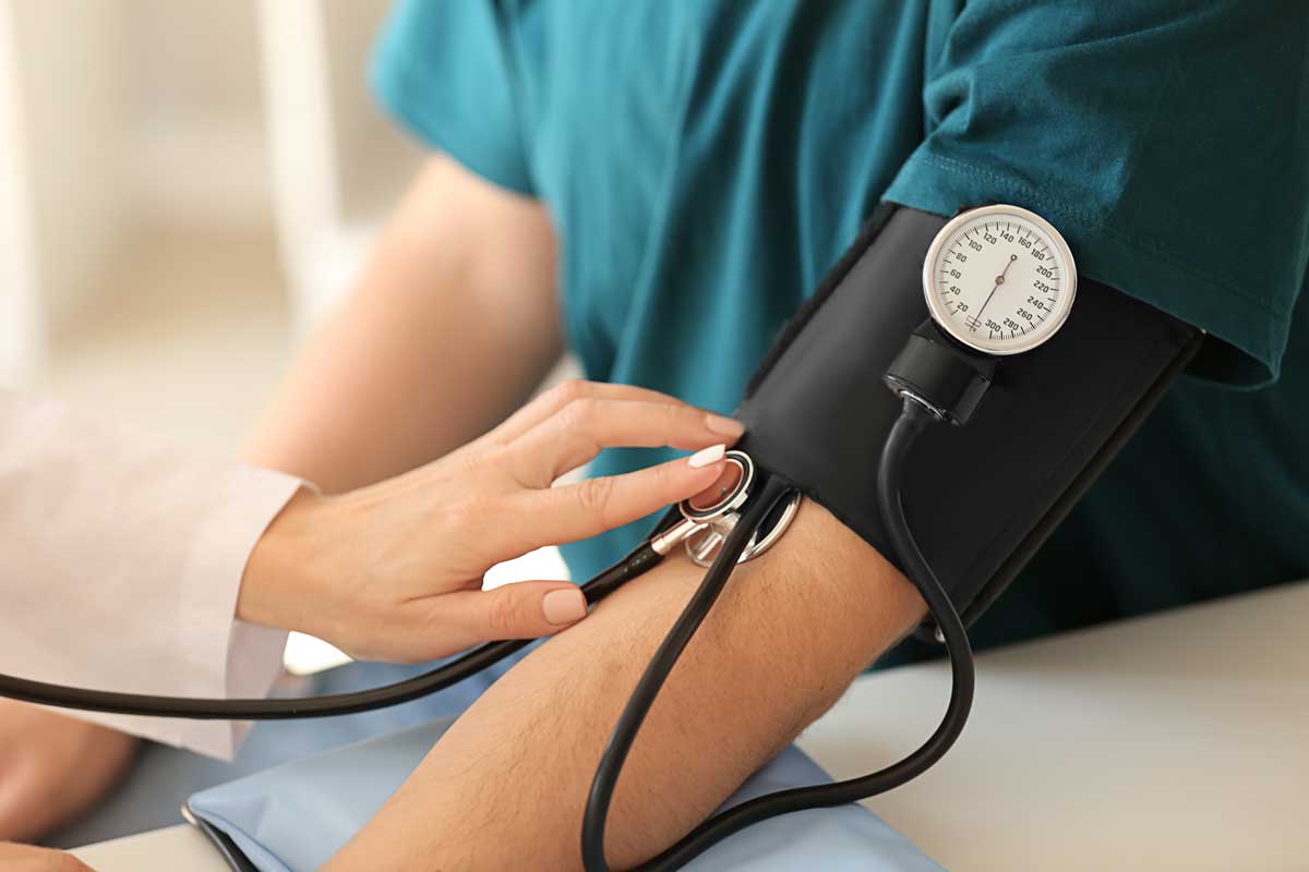 Female healthcare worker measuring blood pressure of male patient for physical exam