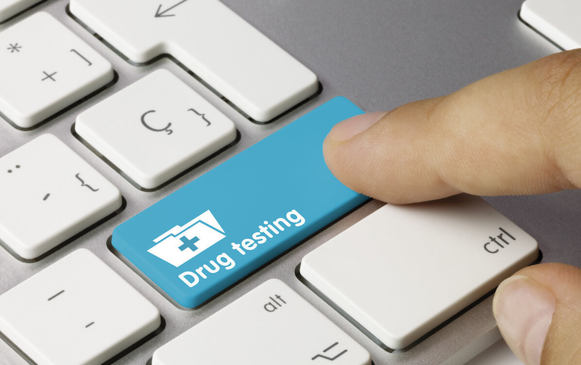 person pushing a keyboard button labeled "Drug Testing"