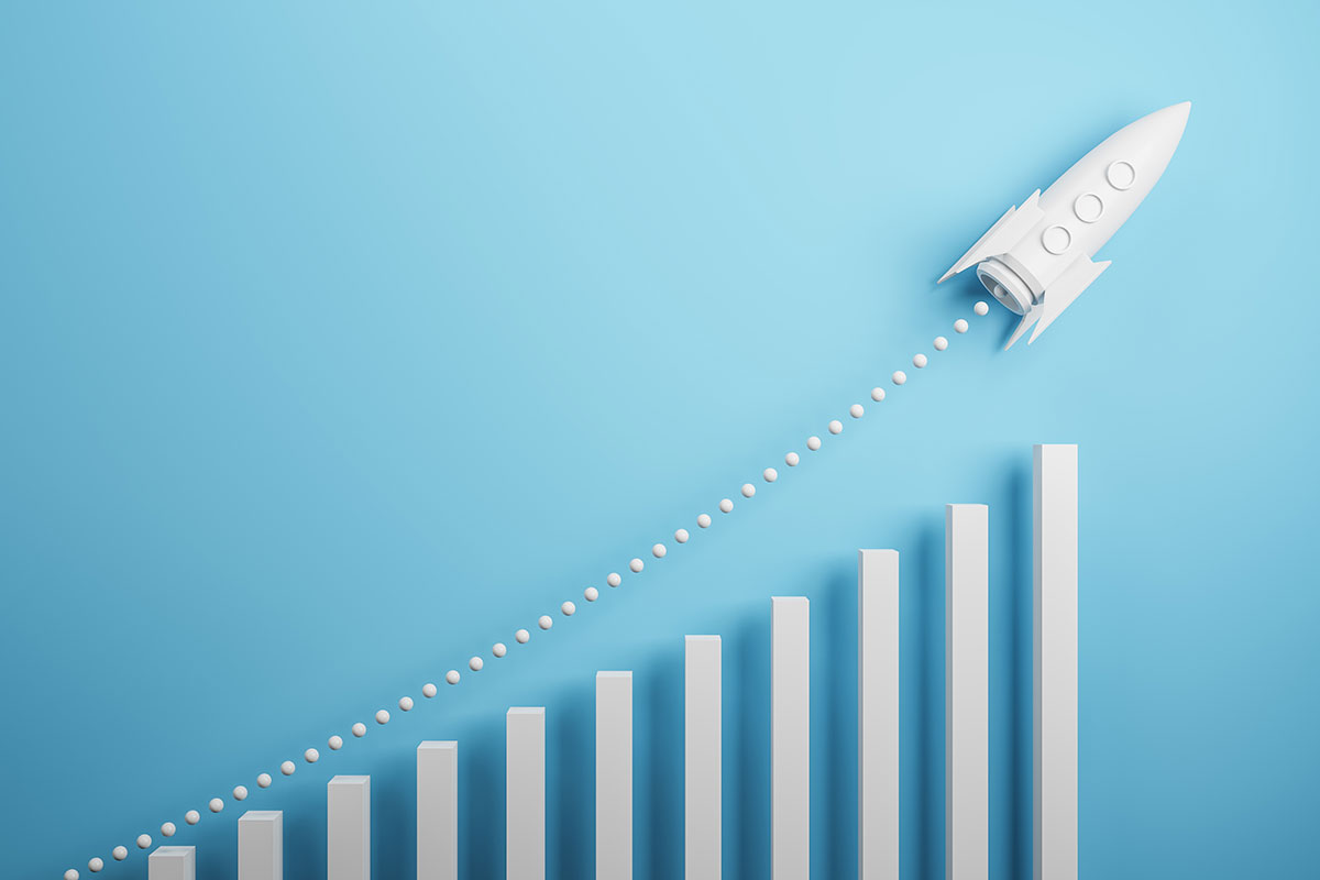 paper rocket ship taking off over an increasing bar graph symbolizing growth