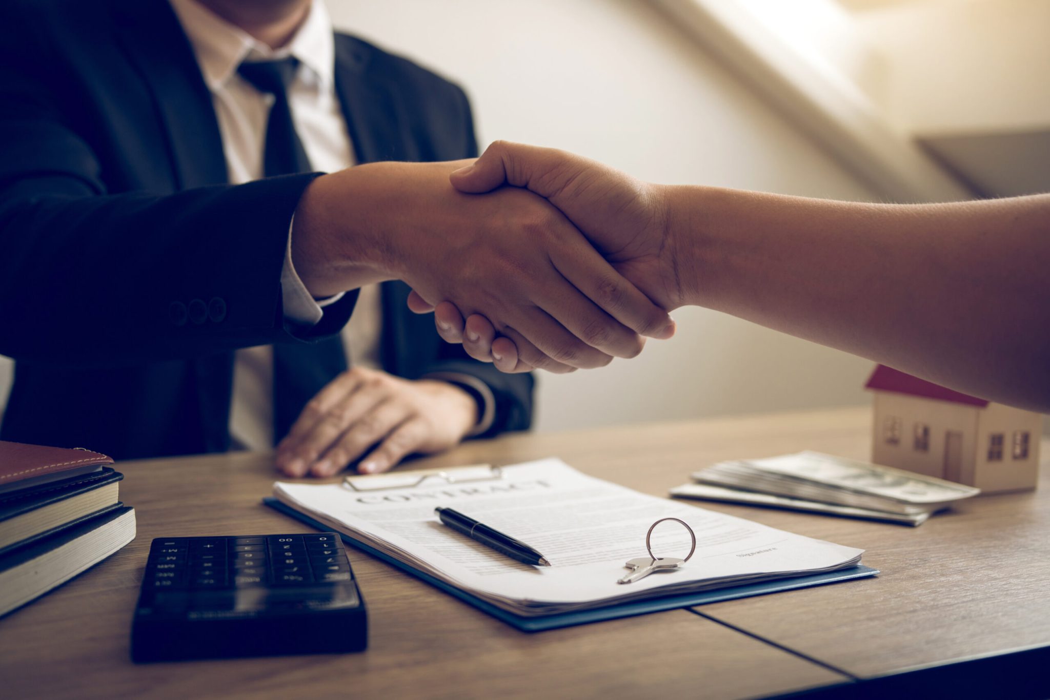 Two people shaking hands over a contract