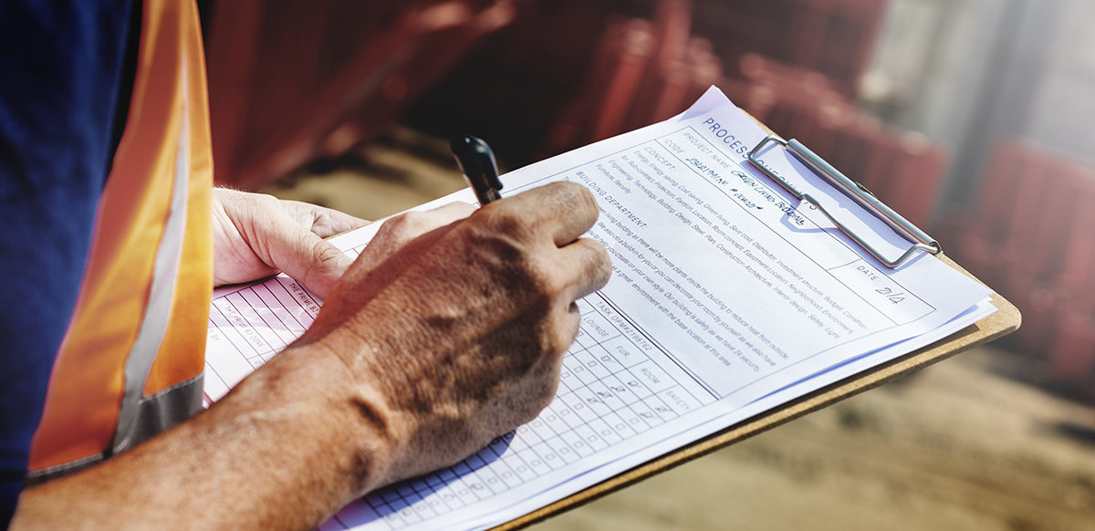 worker wearing a safety vest making notes on a clipboard